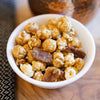 Ellis Bros Pecans caramel popcorn with pecan halves in white bowl on wooden board