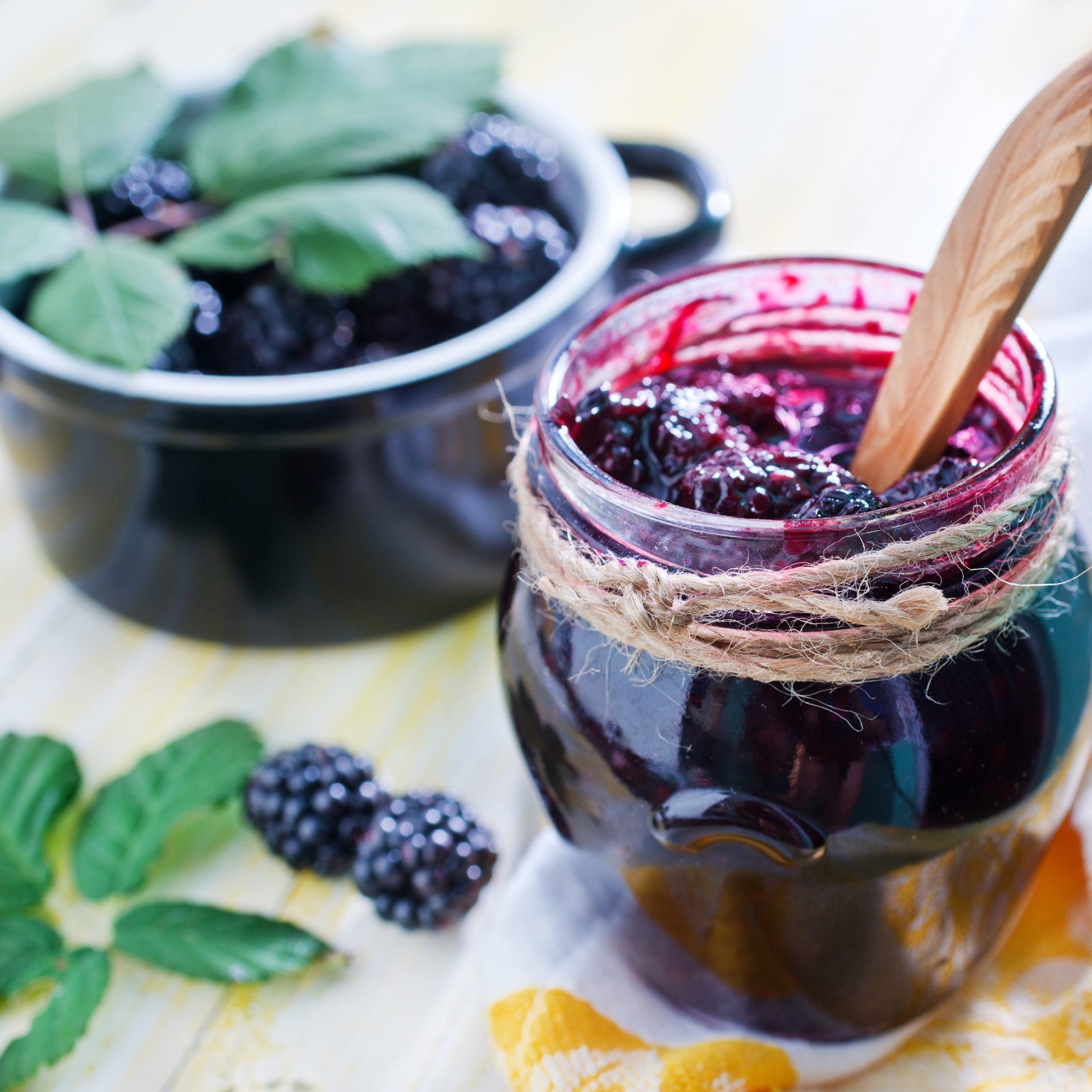 Blackberry Jelly in glass jar with twine and wooden serving spoon